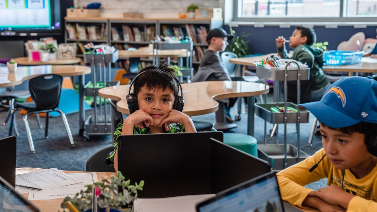 Young students using laptops and headphones in a classroom or after-school program setting in San Ysidro