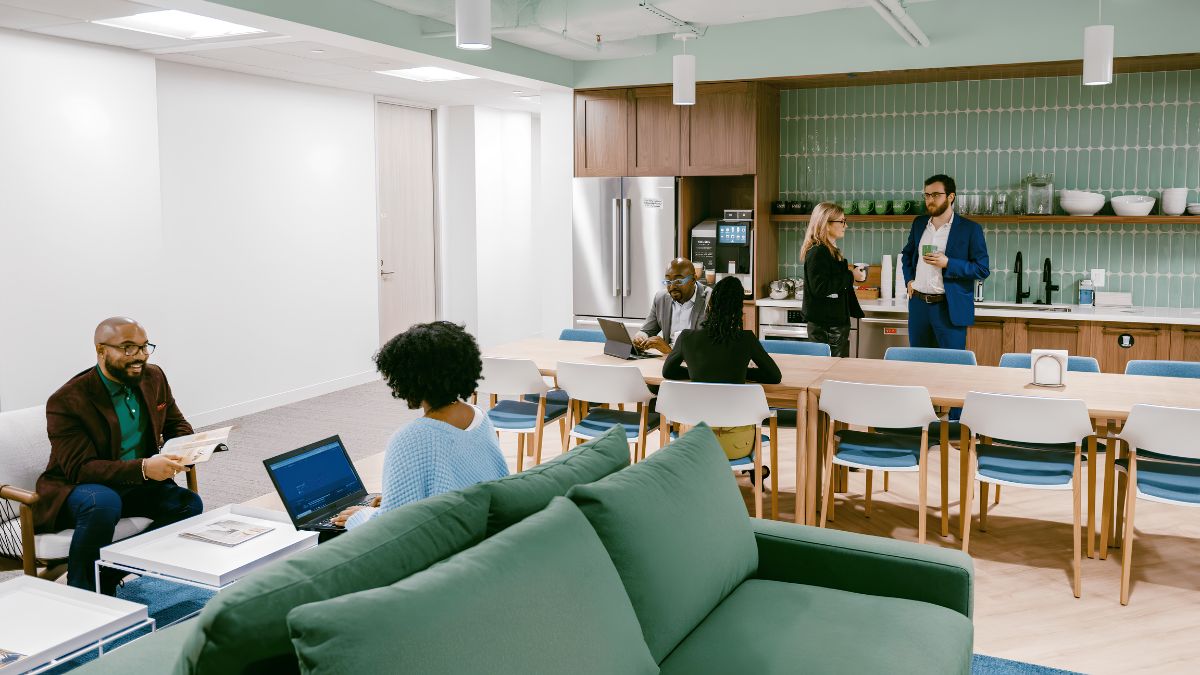 Diverse professionals collaborating in a modern, well-lit office space with a kitchen area, representing a strategic commercial environment for business growth in San Ysidro.