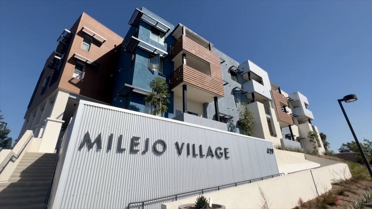 Low-angle exterior view of a modern multifamily apartment building called Milejo Village
