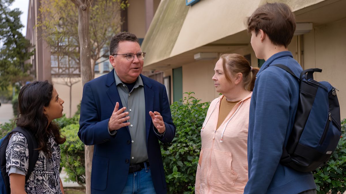 A professional in San Ysidro consulting with local residents outdoors, discussing services before making a hiring decision.