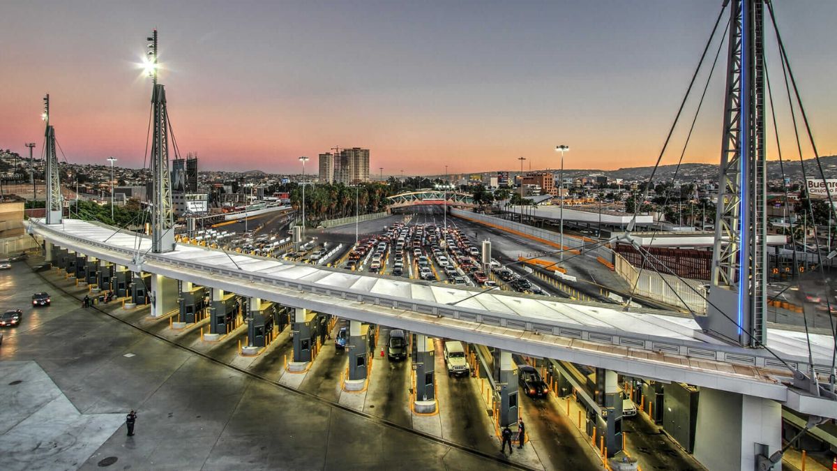 High-angle aerial view of the San Ysidro Port of Entry with lines of vehicles waiting at the border crossing during dusk.