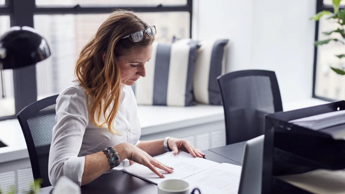A female entrepreneur reviewing a small business budget and financial documents at an office desk.