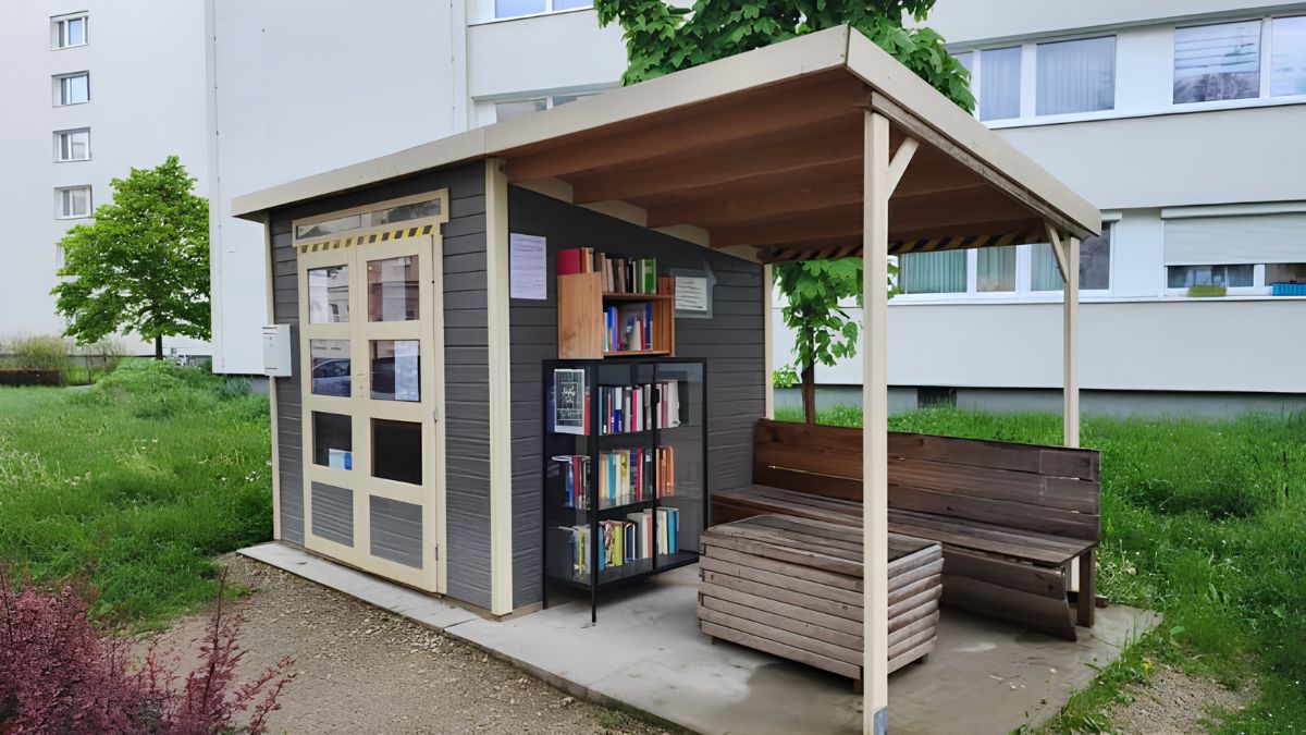 An outdoor community book exchange shed and covered seating area with bookshelves filled with books