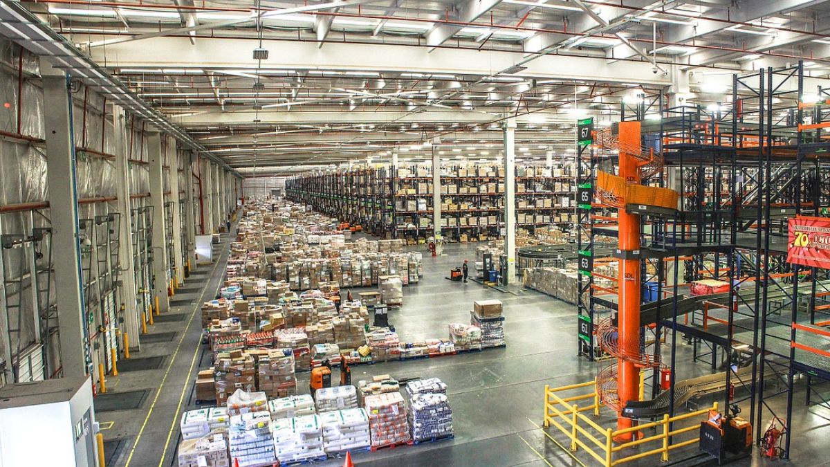 High-angle view of a large, modern industrial warehouse filled with organized storage racks, pallets, and inventory