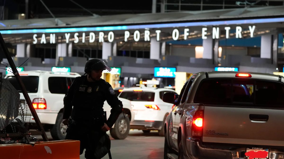A law enforcement officer on duty near vehicles at the San Ysidro Port of Entry at night.
