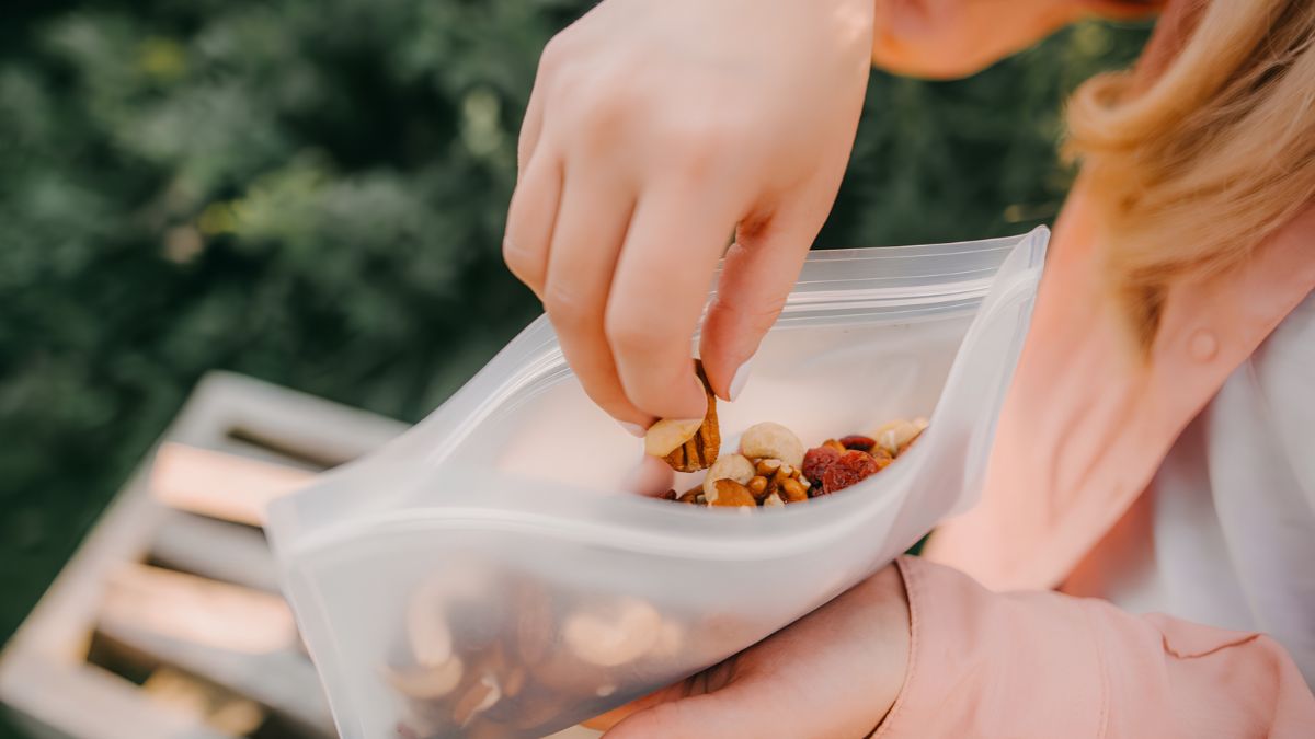 A person taking nuts from a reusable silicone food storage bag, demonstrating sustainable household products in San Ysidro.