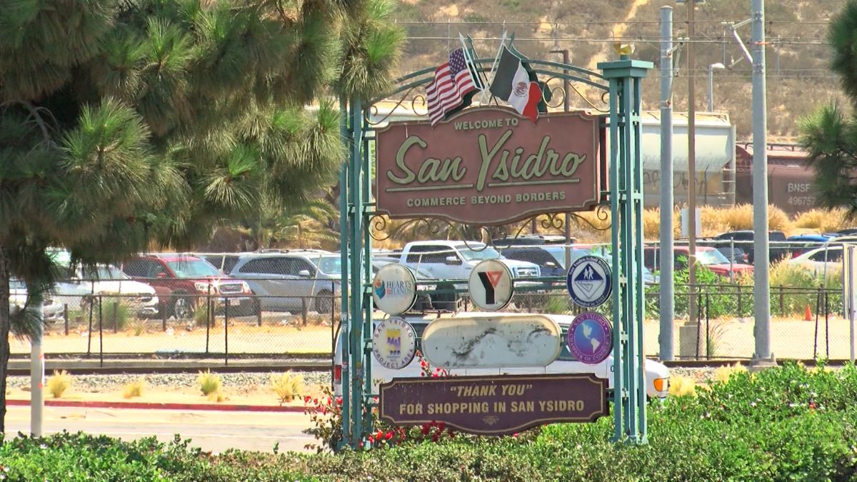 A welcome sign for San Ysidro featuring community logos, US and Mexican flags, and the text "Commerce Beyond Borders".