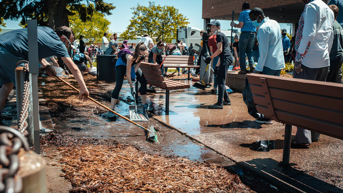 Volunteers working together to clean up a public park area, sweeping pathways and collecting debris to illustrate how to organise a safe and successful community clean-up in San Ysidro.