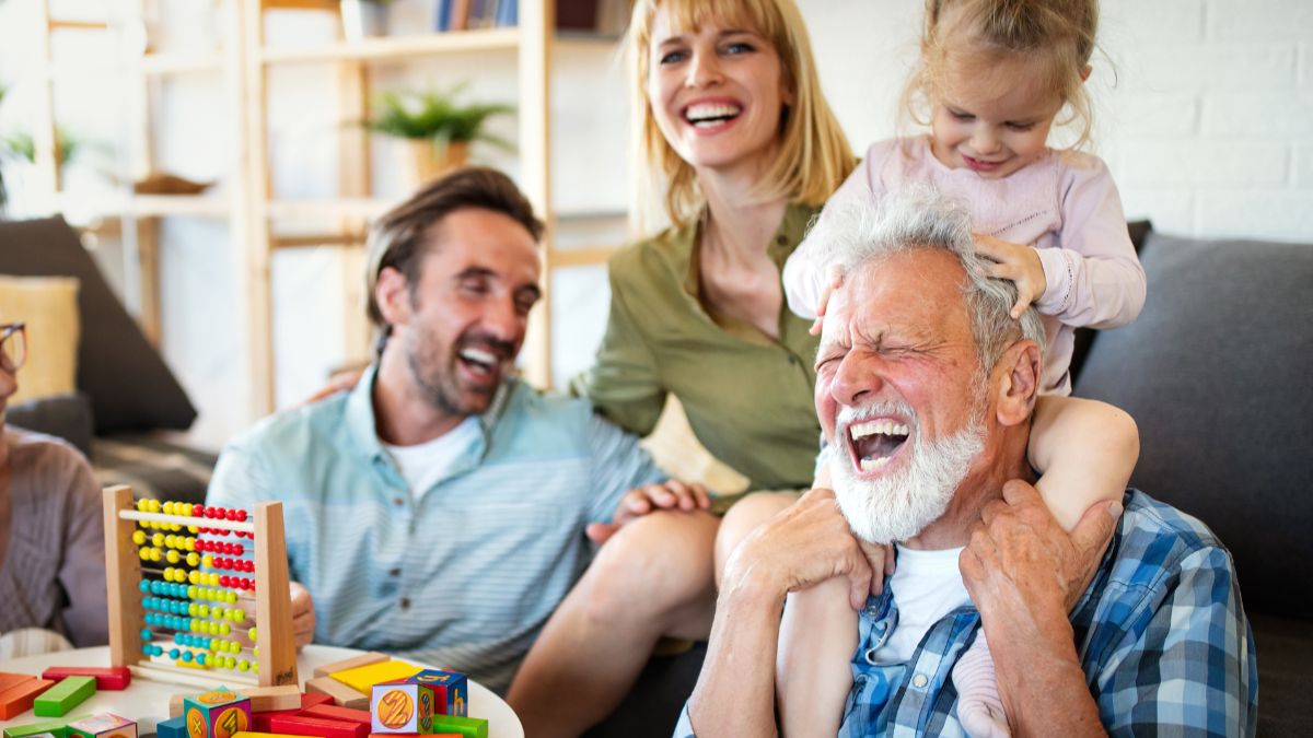 A multi-generational family laughing and smiling together indoors while sharing moments and family traditions.