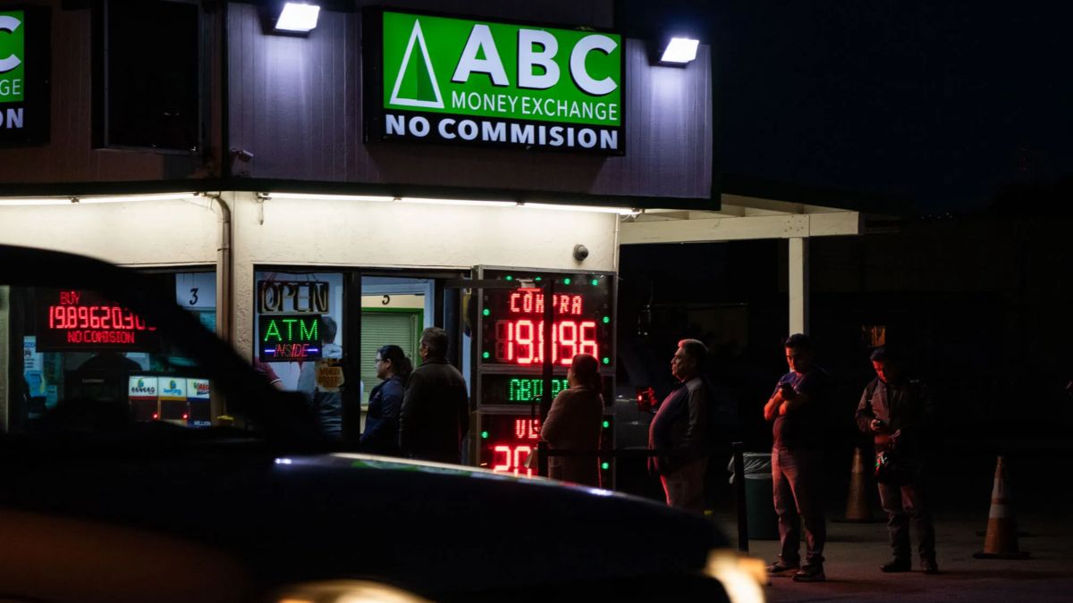 Customers waiting outside a busy San Ysidro money exchange storefront at night, illustrating a business potentially outgrowing its physical space.