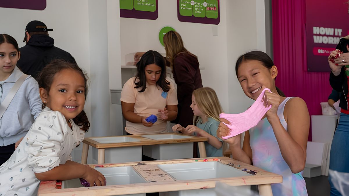 Children smiling while participating in a creative craft workshop playing with pink slime