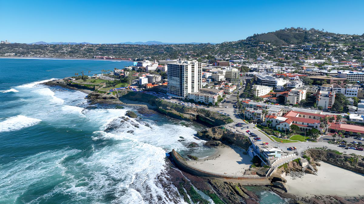 An aerial coastal view showing buildings, neighborhoods, and the ocean shoreline, representing a guide on moving to San Ysidro and daily life.