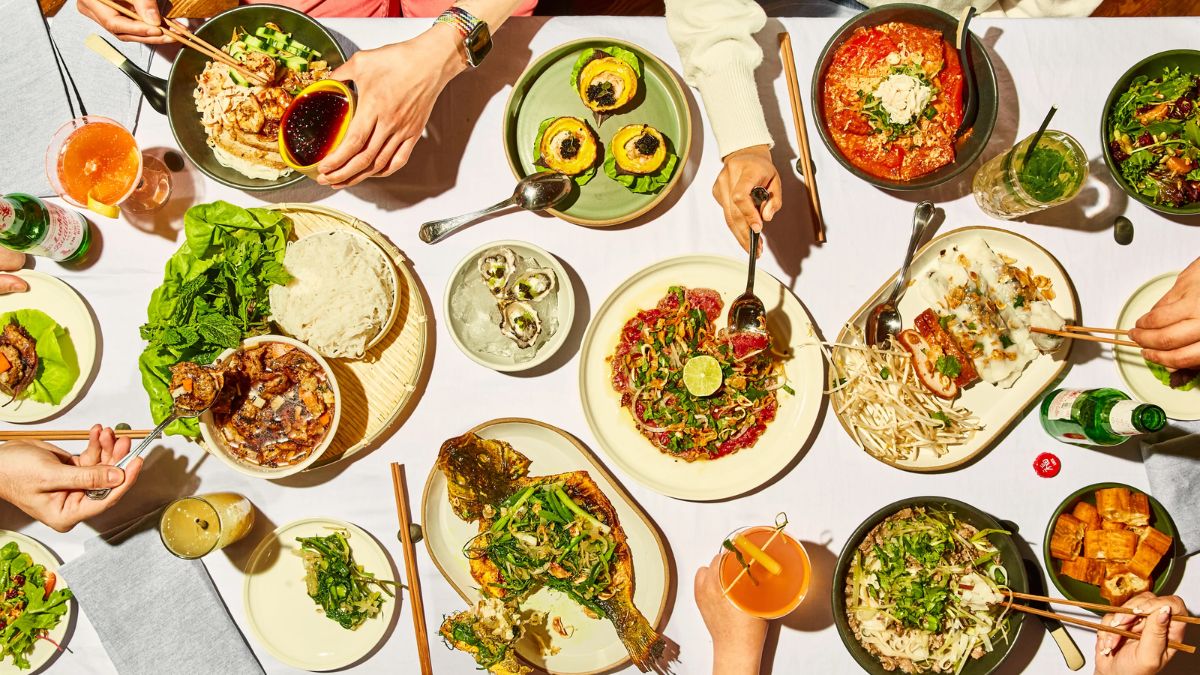 Overhead view of a group of friends sharing a large feast of diverse dishes at a restaurant table