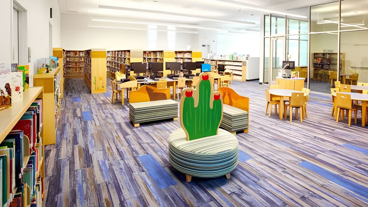 Bright and colorful interior of a modern public library featuring children's seating, book shelves, and computer stations.