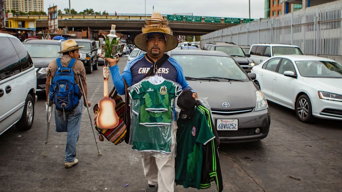 A street vendor carrying items and souvenirs between cars in traffic near the San Ysidro border