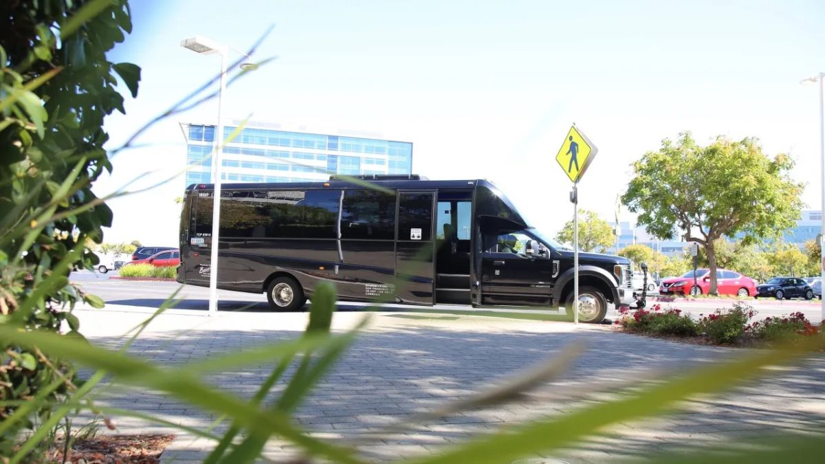 A black shuttle bus parked outdoors near a sidewalk, representing accessible transportation for cross-border travel.