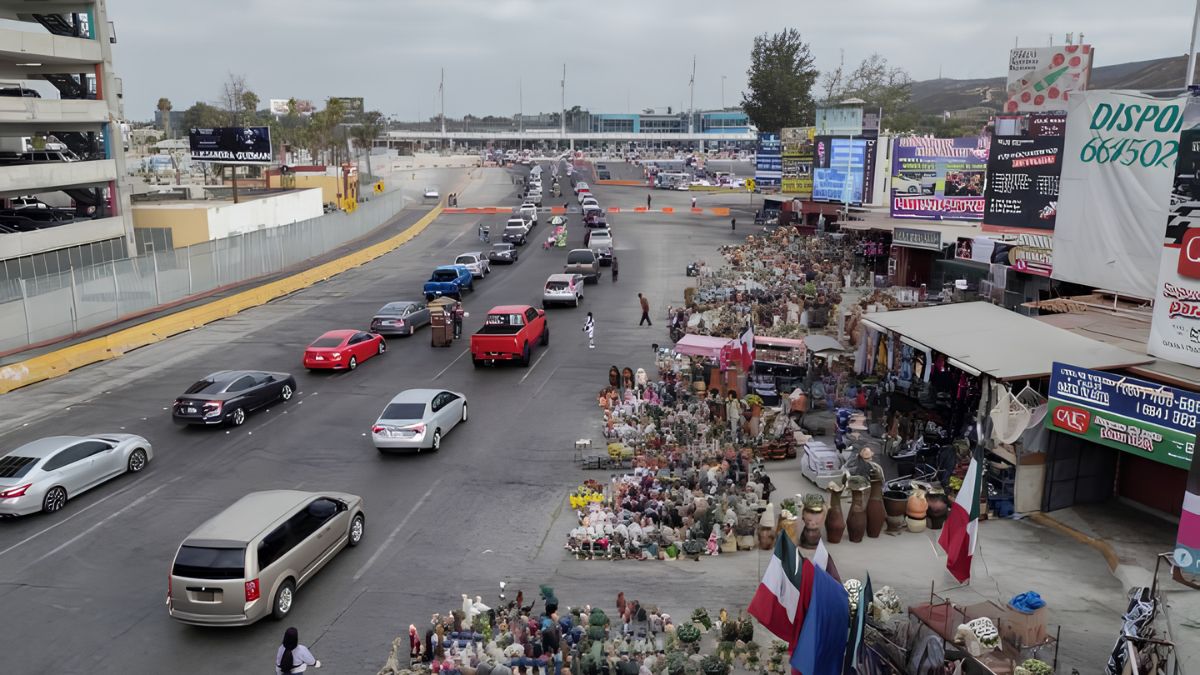 Elevated view of vehicles driving along a street next to local shops, stalls, and billboards in the San Ysidro area.