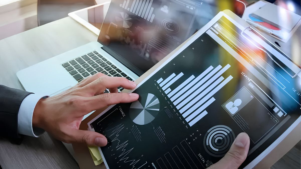 A business owner analyzing charts and customer metrics on a tablet and laptop to secure digital booking and payment systems