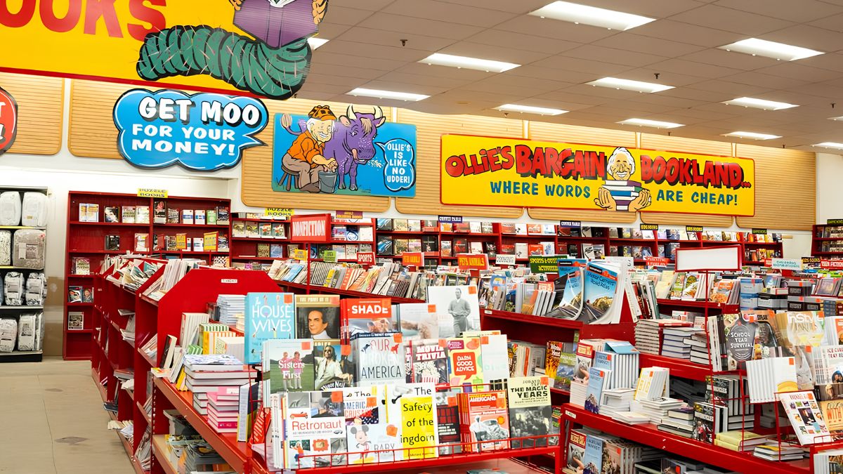 Interior view of a discount bargain bookstore with shelves stocked with books, magazines, and playful promotional signs.