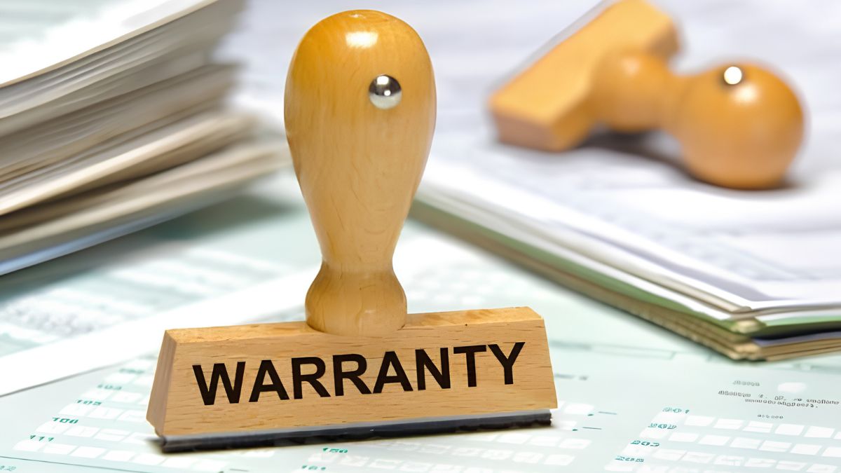 A wooden rubber stamp with the word warranty printed on it resting on documents, representing manufacturer warranties and consumer rights