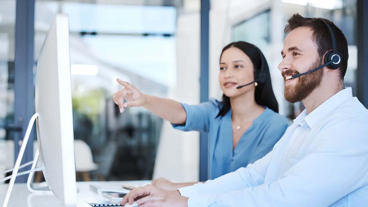 Customer service representatives with headsets working together at a computer to resolve service problems